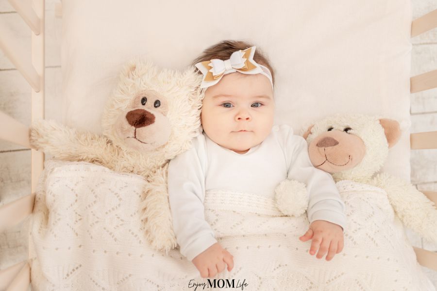 cute little girl in crib with stuffed animals